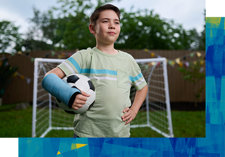 Boy holding soccer ball with cast on right arm.