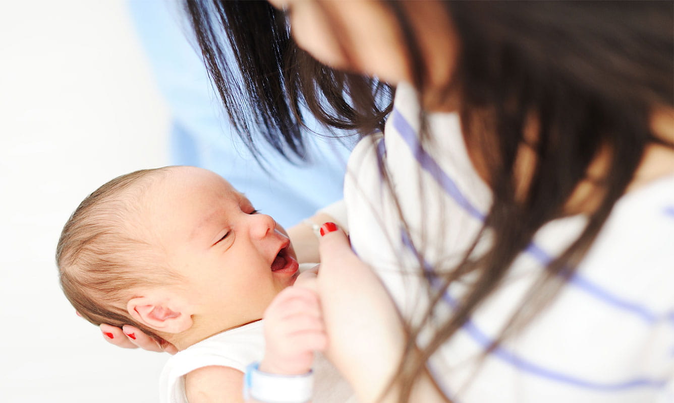mother uses football hold for breastfeeding