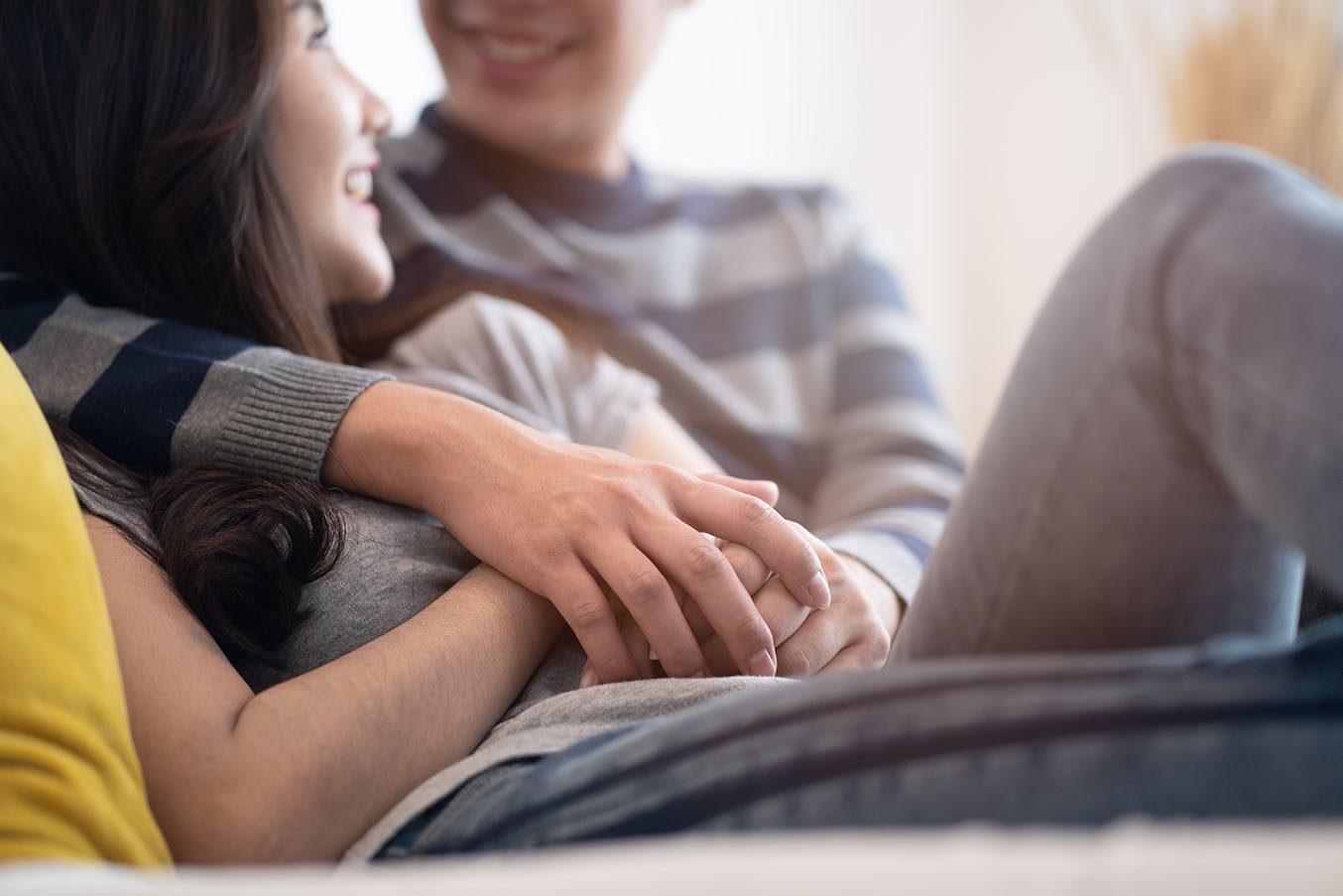 A young couple sits together holding hands.