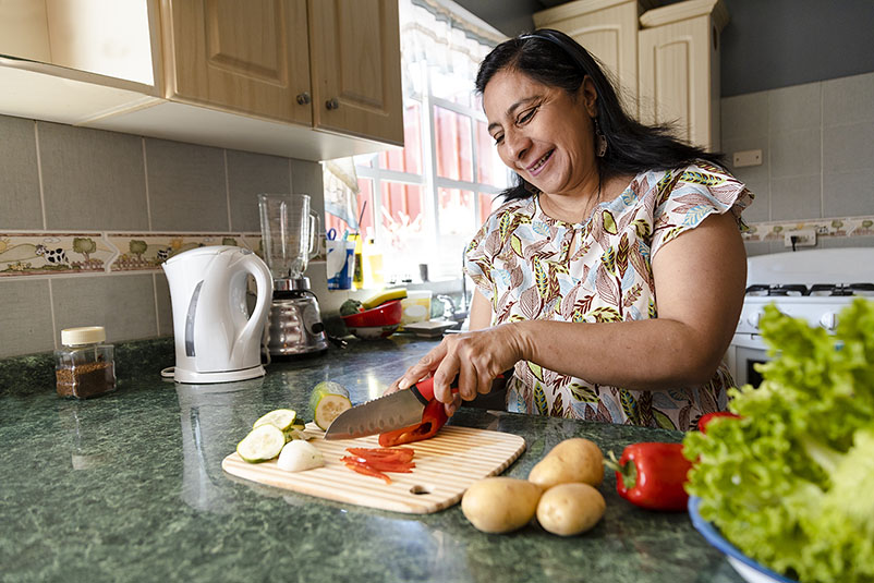 A woman chops fresh vegetables in her kitchen.