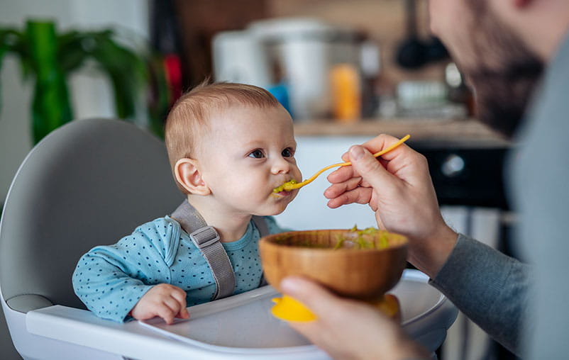 Baby boy being spoon fed by father 