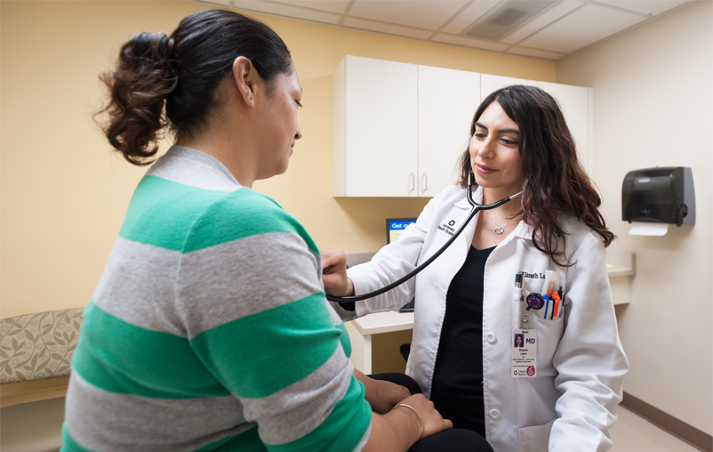University Healthy physician performing routine check-up on female patient.
